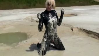 Climax Super Hot Blond Girl in Black Latex Catsuit + High Heels and Sunglasses Bathes in the Mud - Mud Bath Foreskin